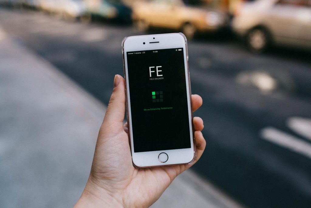 Close-up of a smartphone with an app on screen held by a person in an urban setting.